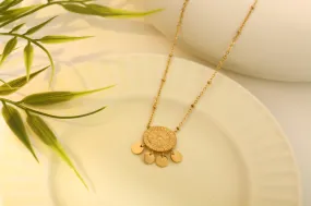 Goldene Halskette mit rundem Anhänger und Quasten